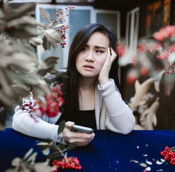 Dealing With The Toxicity Of Online Dating. Picture of sad girl with a mobile phone in her hand.