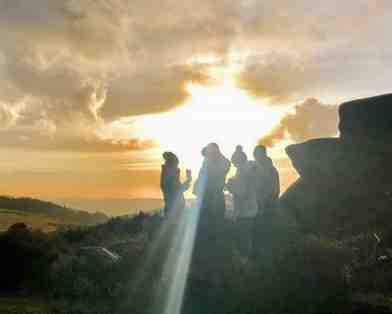 What Is Spirituality? Are We In Danger Of Throwing Out The Baby With The Bathwater? Photo of people praying on a mountain bathed in sunlight.