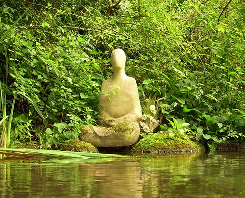 So What Exactly Does It Mean to Wake Up - What Is "Enlightenment"? Photo of statue meditating by water.