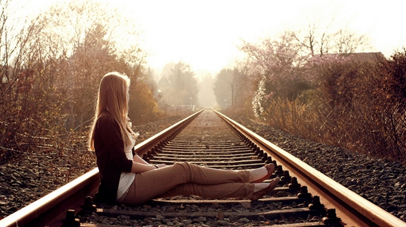 Are You Waiting For Change? Always Looking Forward Or Back, Anywhere But Now! Photo of a young woman sitting with her legs across a railway looking up the track.
